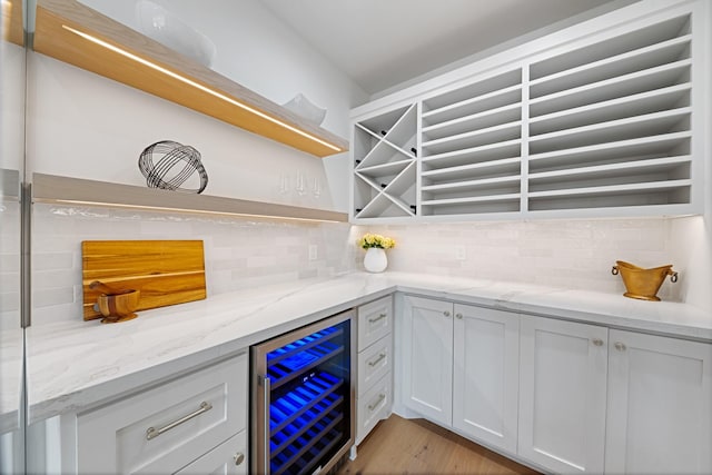 interior space featuring tasteful backsplash, light stone countertops, white cabinets, and beverage cooler