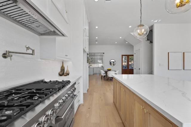 kitchen with custom exhaust hood, decorative light fixtures, light wood-type flooring, light stone countertops, and high end stove