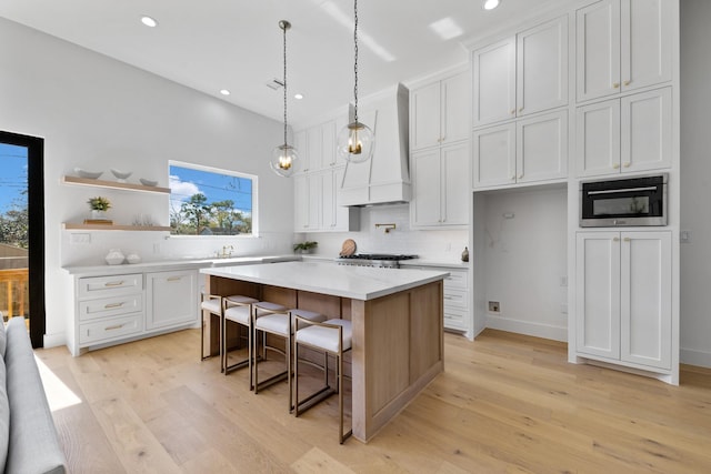 kitchen featuring white cabinetry, custom range hood, a breakfast bar, and a kitchen island