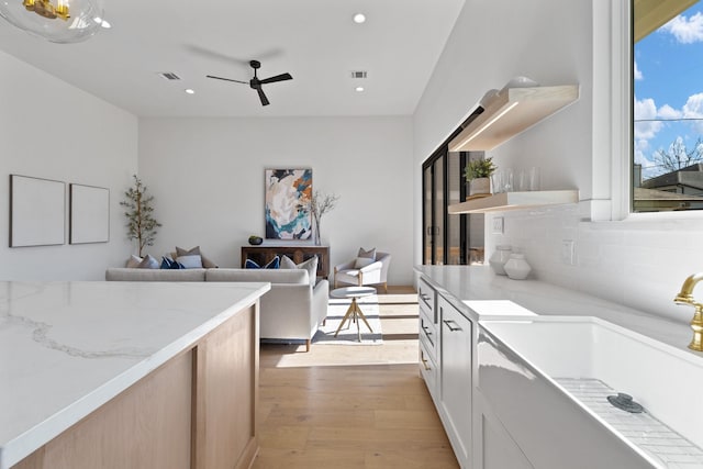 kitchen with light brown cabinetry, sink, ceiling fan, light hardwood / wood-style floors, and decorative backsplash