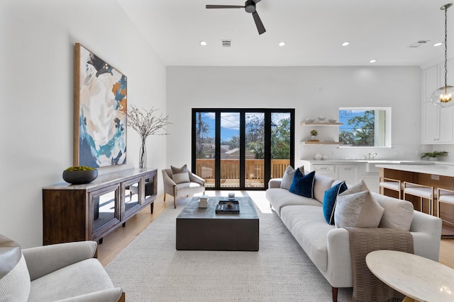 living room with ceiling fan with notable chandelier and light wood-type flooring