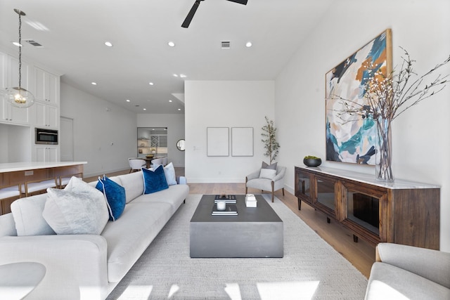 living room with light hardwood / wood-style flooring and ceiling fan