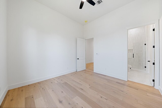 unfurnished bedroom featuring high vaulted ceiling, light hardwood / wood-style flooring, ceiling fan, and ensuite bath