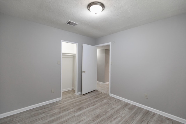 unfurnished bedroom featuring light wood-style floors, visible vents, a closet, and baseboards