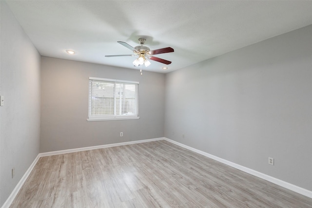 empty room featuring baseboards, light wood finished floors, and ceiling fan