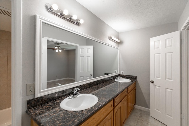 full bathroom featuring a sink, a textured ceiling, double vanity, and tile patterned floors