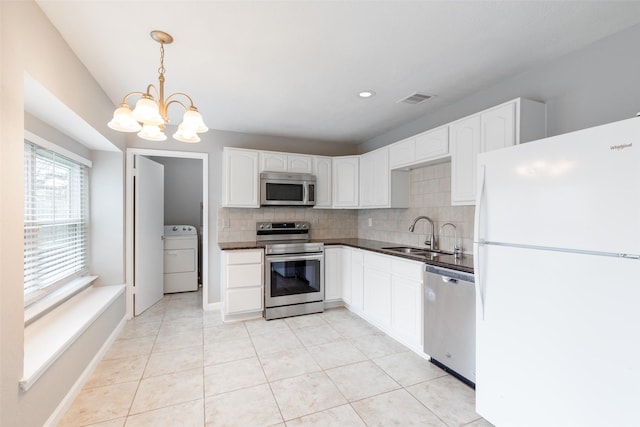 kitchen featuring dark countertops, visible vents, washer / dryer, stainless steel appliances, and a sink