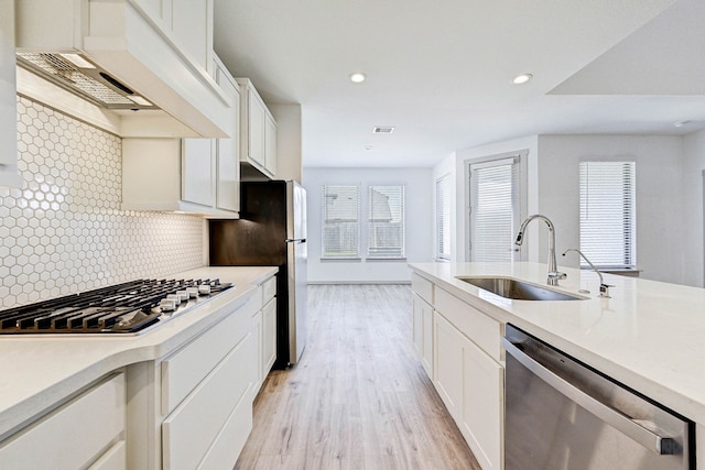 kitchen featuring stainless steel appliances, sink, white cabinets, and backsplash