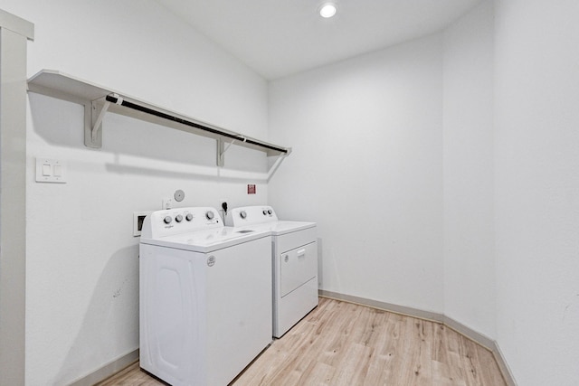 clothes washing area with light hardwood / wood-style flooring and washer and clothes dryer