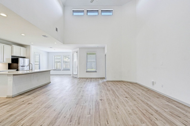 unfurnished living room featuring a towering ceiling and light hardwood / wood-style flooring