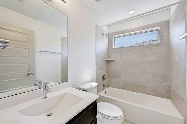 full bathroom featuring tiled shower / bath, vanity, and toilet