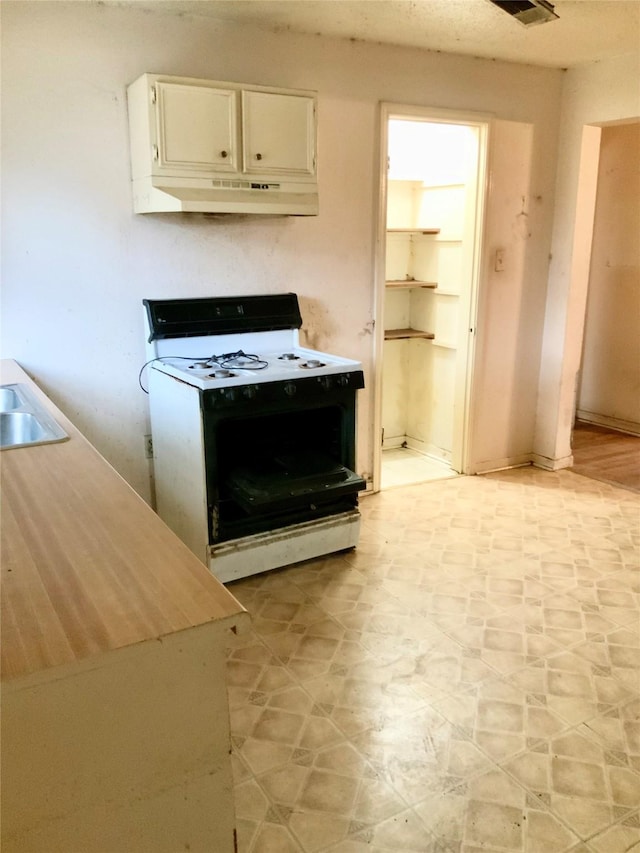 kitchen featuring white cabinetry, white range oven, and sink