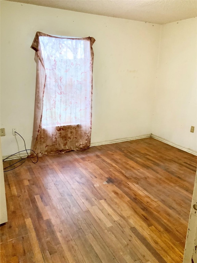 spare room featuring hardwood / wood-style floors and a textured ceiling