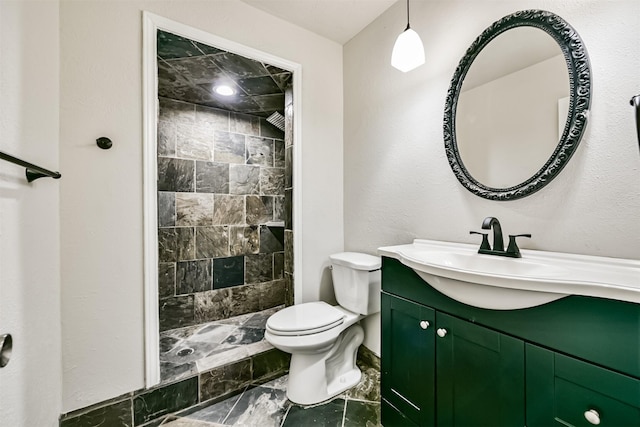 bathroom with vanity, a tile shower, and toilet