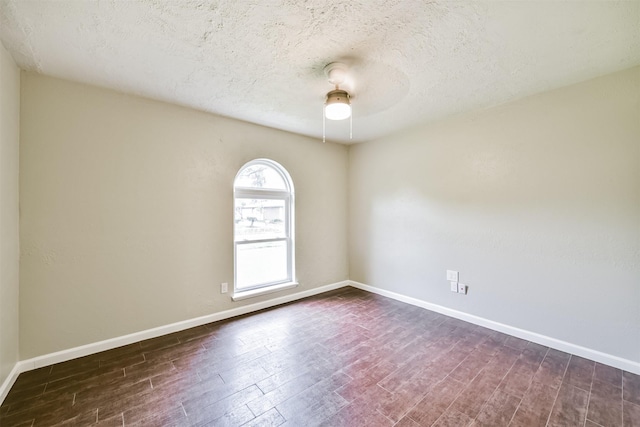 spare room featuring ceiling fan, dark wood-type flooring, and a textured ceiling