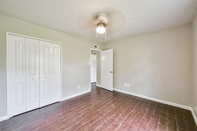 unfurnished bedroom featuring ceiling fan, dark hardwood / wood-style floors, a closet, and a textured ceiling