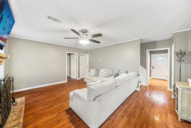 living room with crown molding, ceiling fan, wood-type flooring, and a fireplace