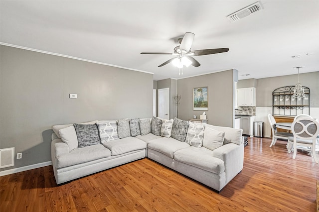 living room with hardwood / wood-style floors, ceiling fan with notable chandelier, and ornamental molding