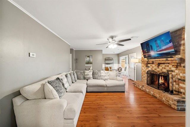 living room with crown molding, ceiling fan, hardwood / wood-style floors, and a brick fireplace