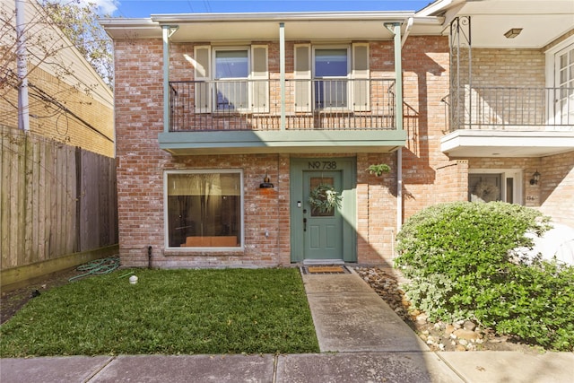 multi unit property featuring a balcony and a front yard