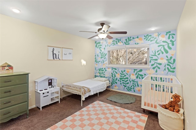 carpeted bedroom with a nursery area and ceiling fan