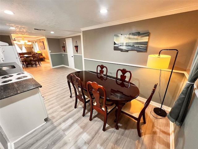 dining room featuring crown molding, light hardwood / wood-style floors, and a textured ceiling