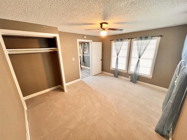 unfurnished bedroom with light colored carpet, a textured ceiling, ceiling fan, and a closet