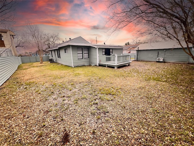 back house at dusk featuring a yard and a deck