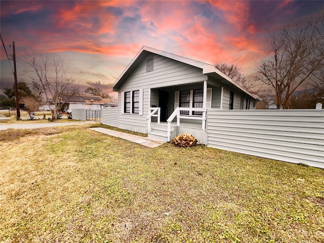 back house at dusk featuring a yard