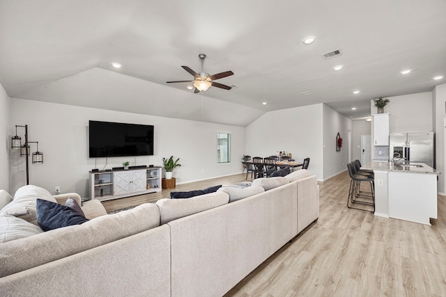 living room with ceiling fan, lofted ceiling, sink, and light hardwood / wood-style floors