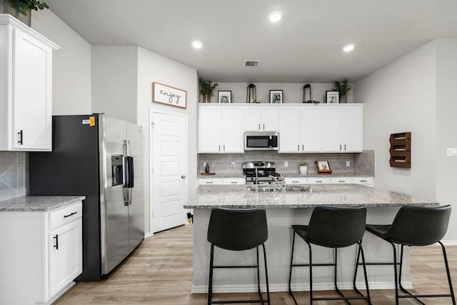 kitchen featuring white cabinetry, light stone counters, and stainless steel appliances