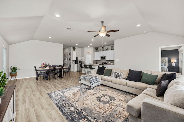 living room featuring lofted ceiling, light hardwood / wood-style floors, and ceiling fan