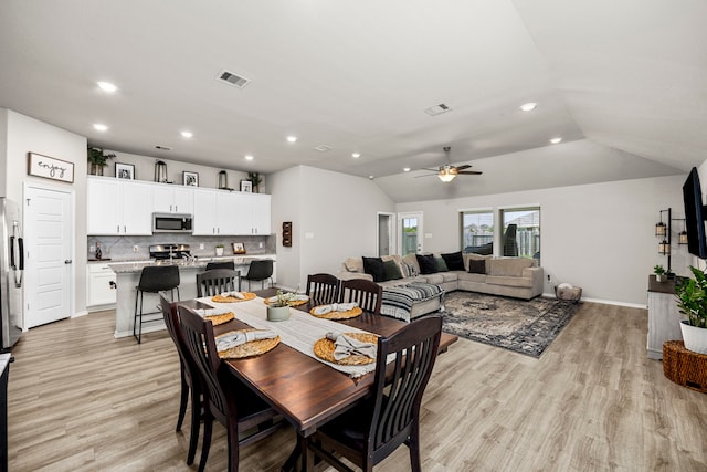 dining area with light hardwood / wood-style flooring, vaulted ceiling, and ceiling fan