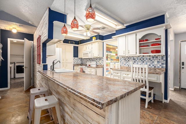 kitchen with sink, white appliances, backsplash, and a kitchen bar