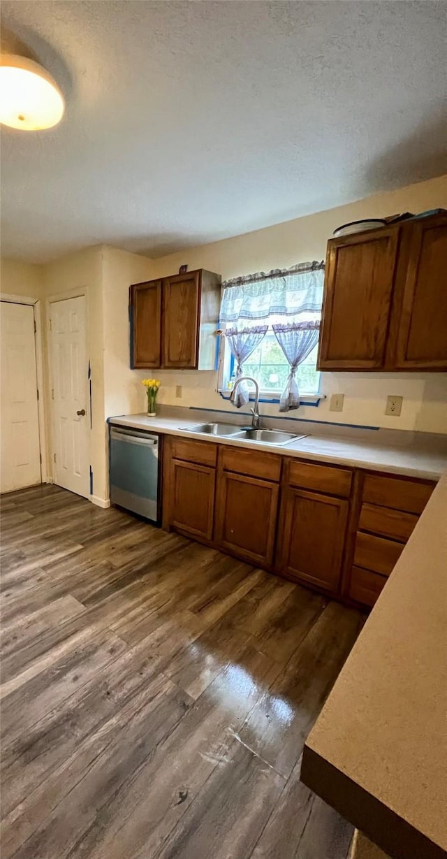 kitchen featuring stainless steel dishwasher, dark hardwood / wood-style floors, sink, and a textured ceiling