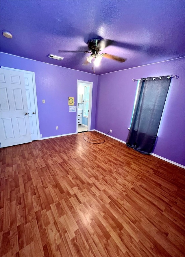 unfurnished bedroom with ceiling fan, connected bathroom, hardwood / wood-style floors, and a textured ceiling