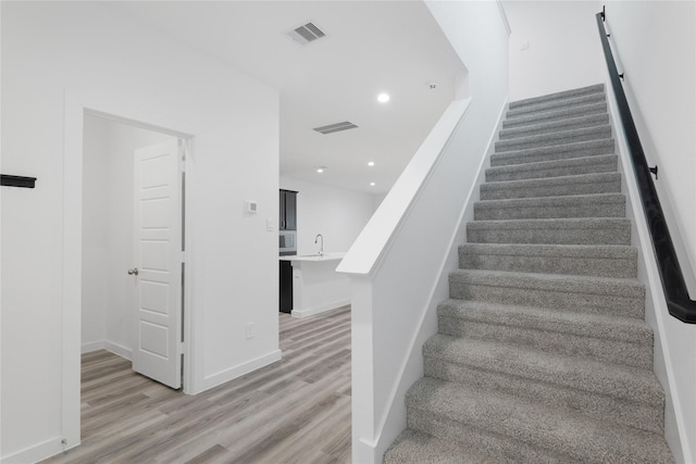 stairs featuring wood-type flooring and sink