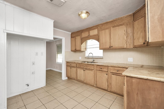 kitchen featuring crown molding, sink, a wealth of natural light, and light tile patterned flooring