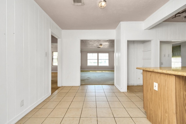 interior space featuring light colored carpet, a textured ceiling, and wood walls