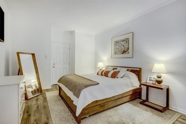 bedroom featuring crown molding and light wood-type flooring