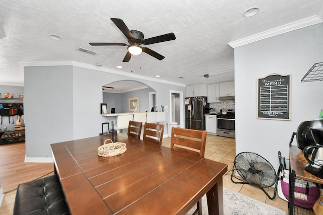 tiled dining room with crown molding, ceiling fan, and a textured ceiling