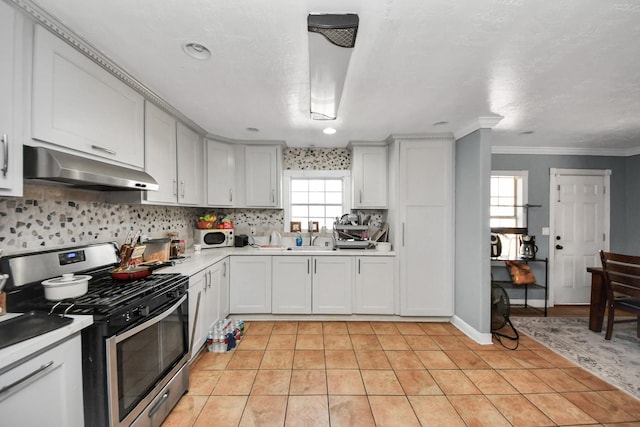 kitchen featuring light tile patterned floors, ornamental molding, decorative backsplash, white cabinets, and gas range