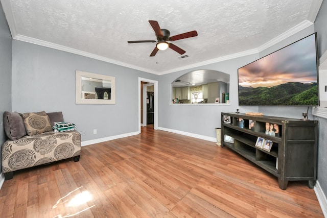 sitting room with hardwood / wood-style floors, ornamental molding, a textured ceiling, and ceiling fan