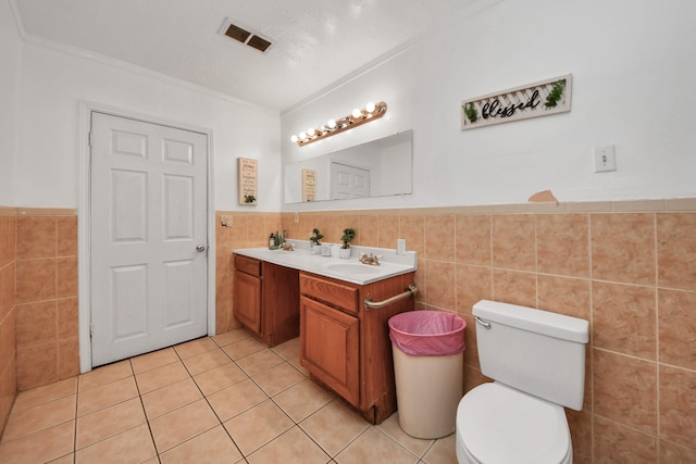 bathroom featuring tile walls, ornamental molding, vanity, toilet, and tile patterned floors