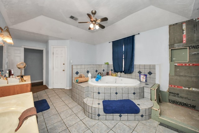 bathroom featuring tiled tub, a tray ceiling, tile patterned floors, and ceiling fan