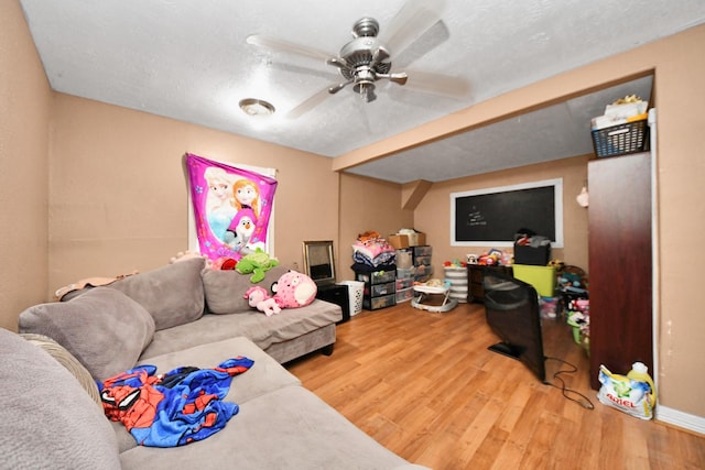 living room featuring ceiling fan, hardwood / wood-style floors, and a textured ceiling