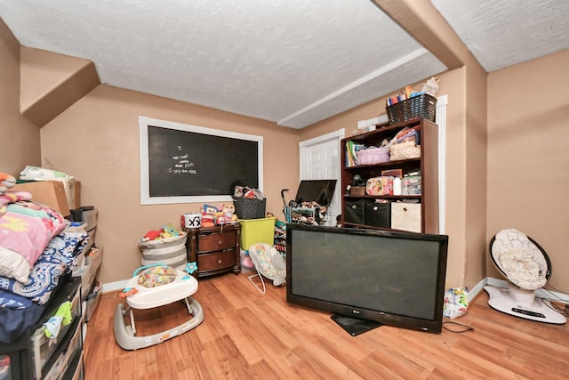 rec room with a textured ceiling and light wood-type flooring