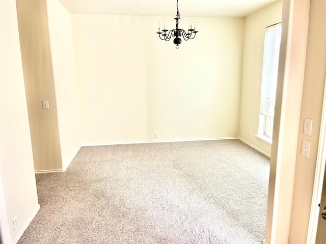 empty room with carpet and an inviting chandelier