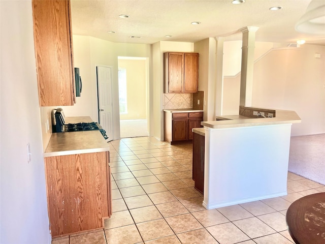 kitchen with light tile patterned floors, backsplash, decorative columns, and range