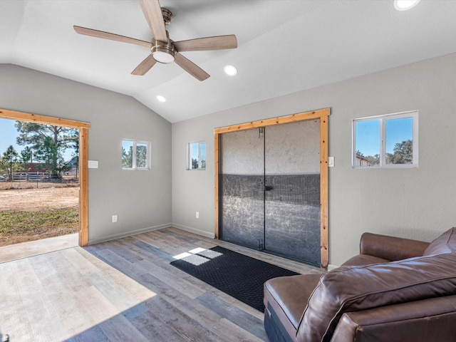 living room featuring ceiling fan, light hardwood / wood-style floors, and vaulted ceiling